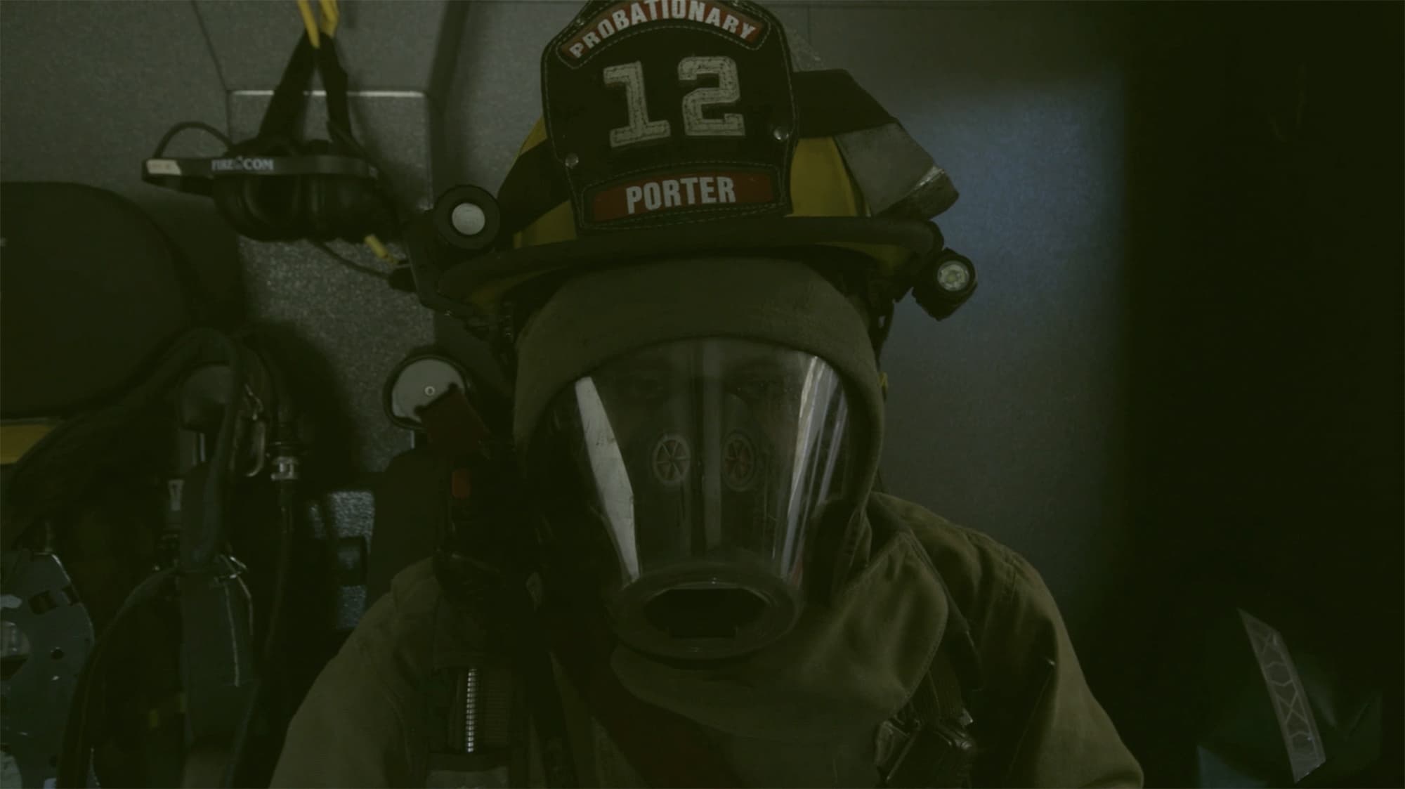 A firefighter in mask and helmet, looking directly at the camera